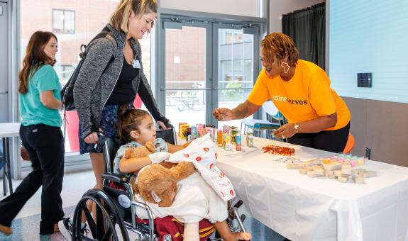 teddy bear clinic image with child in wheelchair and Spire volunteers